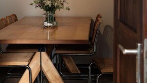 A wooden dining table with chairs, a hanging pendant light, and a vase with flowers. - La Stalla by Interhome (Faido)