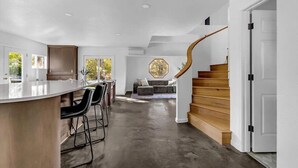 A modern kitchen with a bar area, a staircase, and a living room with a view. - Montgomery Ranch | Stunning Lake House (Redding)