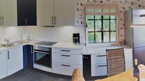 A modern kitchen with white cabinets, a built-in oven, a coffee maker, and a window with a view of greenery. - Haus-Zauberblau by Interhome (Groß Schoritz)