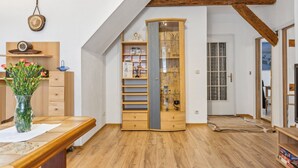 Une pièce mansardée chaleureuse avec des poutres apparentes, une bibliothèque intégrée et une grande fenêtre.