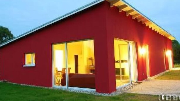 Um edifício vermelho com teto plano, grandes portas de vidro e uma pequena janela.