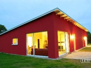 A red building with a flat roof, large glass doors, and a small window. - in Karnin by Interhome (Karnin)
