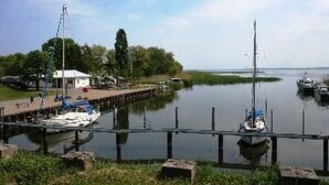 Um areal calmo com um cais, barcos e um pequeno edifício.