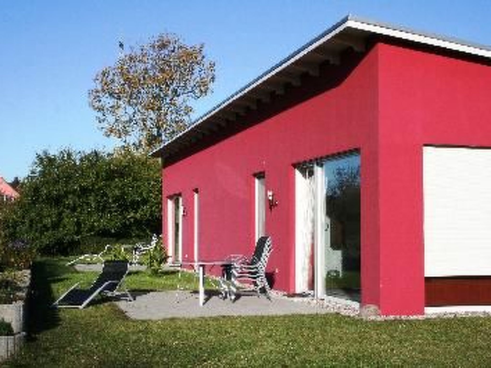 Een rood gebouw met een overdekte patio, zitplaatsen buiten en een boom op de achtergrond.