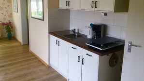 A compact kitchen with white cabinets, a stainless steel sink, and a coffee maker.