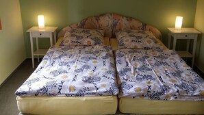 A double bed with patterned bedding, two bedside tables with lamps, and a green wall.
