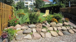 A garden with a lawn, a wooden fence, and a chair. - Charmante Wohnung in Malchow by Interhome (Göhren-Lebbin)
