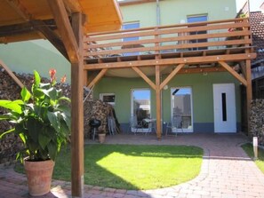 A covered patio with a wooden pergola, a small lawn, and a potted plant. - Charmante Wohnung in Malchow by Interhome (Göhren-Lebbin)