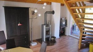Ein Zimmer mit Holzboden, Kamin, Fernseher und Treppe.