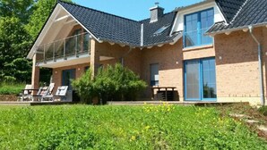 A two-story house with a balcony, brick exterior, and large windows. - Apartment Anker by Interhome (Baabe)