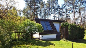 Et lille hus med saddeltag og solcelle på siden.