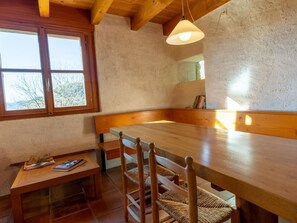 Ein Holztisch mit Stühlen, einer Bank und einem kleinen Tisch mit Büchern und einer Zeitschrift.