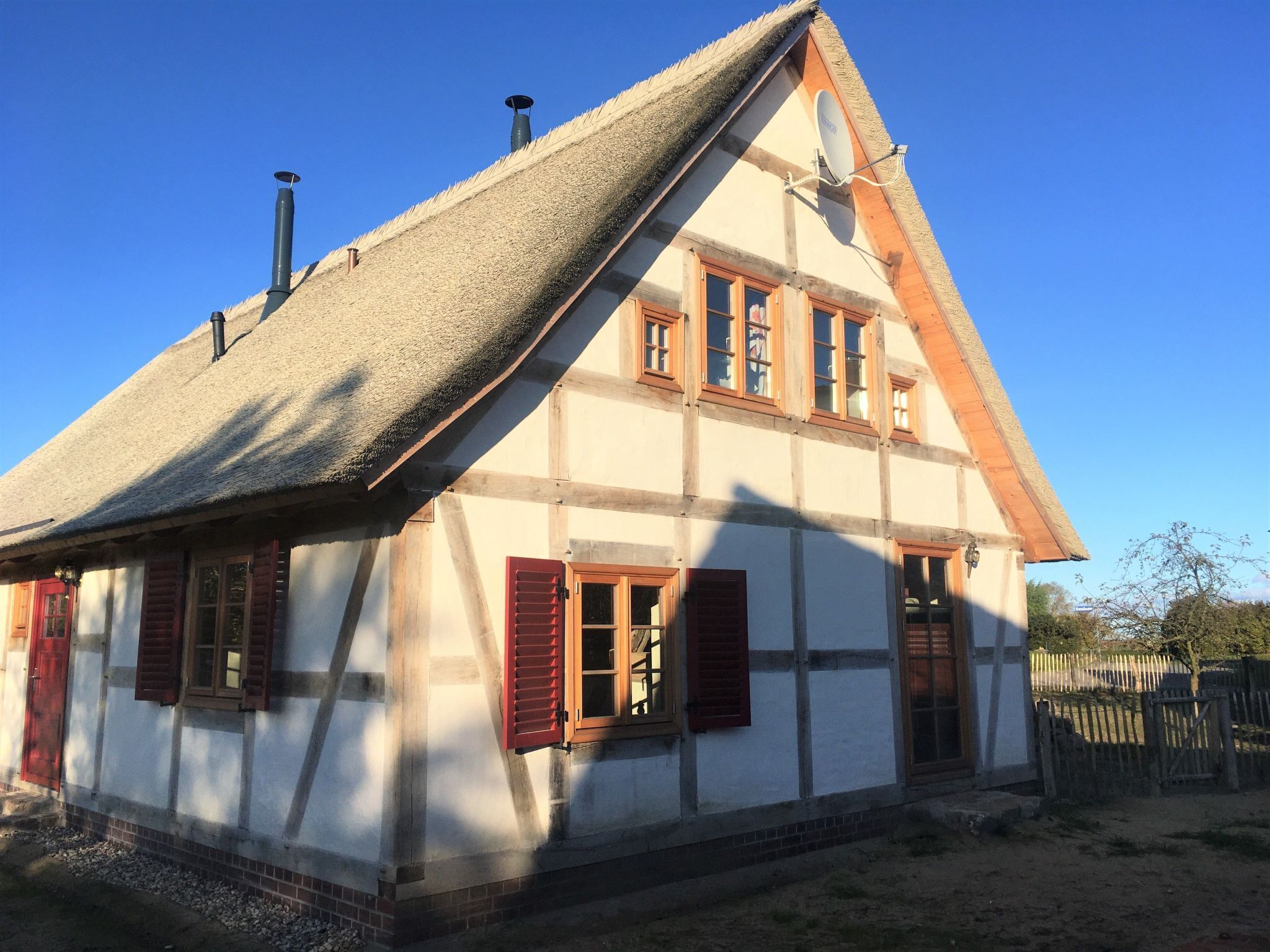 A traditional half-timbered house with a steeply pitched roof, multiple chimneys, and a satellite dish.