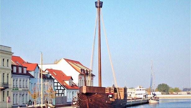 Un gran barco atracado en un puerto con edificios y embarcaciones más pequeñas cerca.