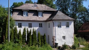 Una casa de dos pisos con fachada blanca y techo inclinado.