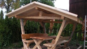 Un espacio de estar al aire libre con bancos y una mesa, rodeado de follaje.