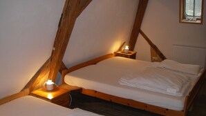 Una habitación con dos literas de madera, cada una con una mesita de noche y una vela encendida.