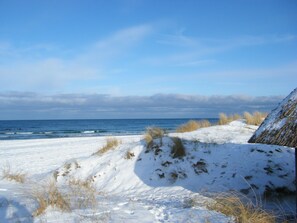 Ein verschneiter Strand mit freiem Blick auf das Meer und entfernte Wolken.