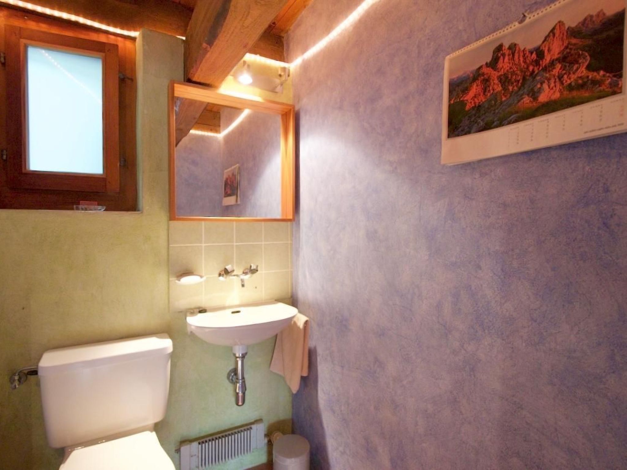 A bathroom with a toilet, sink, and mirror.