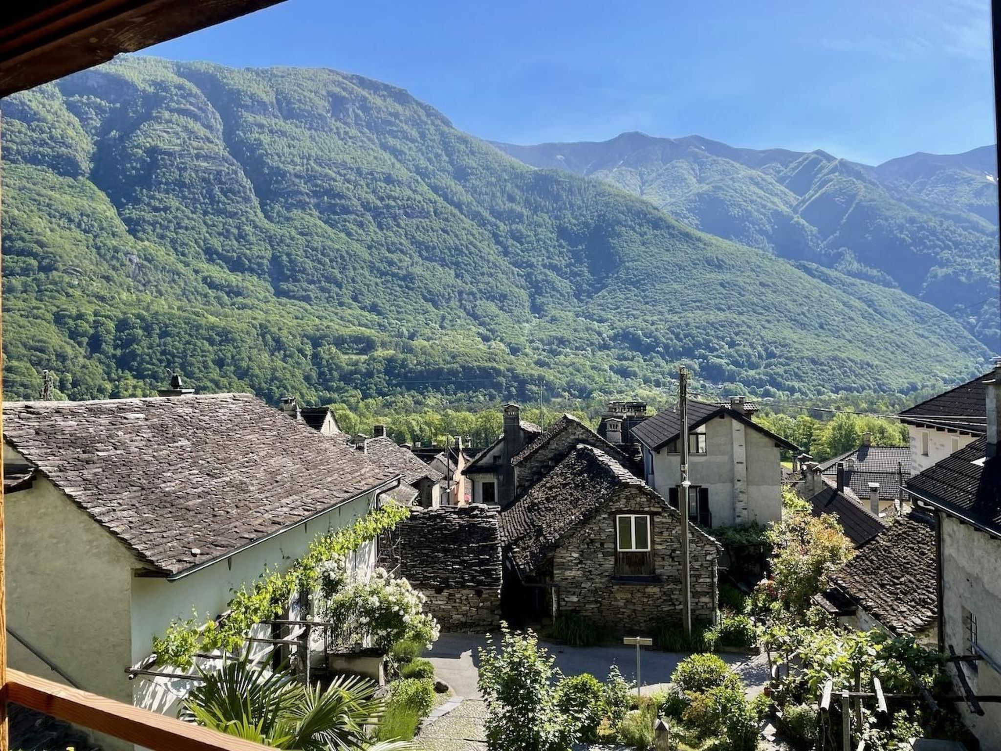 Vila com edifícios de pedra e montanhas ao fundo.