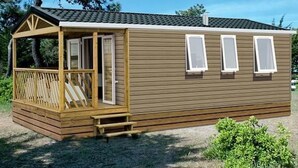 Une petite cabane à un seul étage, dotée d’une terrasse en bois, d’un porche couvert et de trois fenêtres.