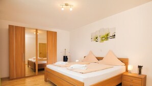 Een slaapkamer met een houten bed, een nachtkastje, een spiegel en een schilderij aan de muur.