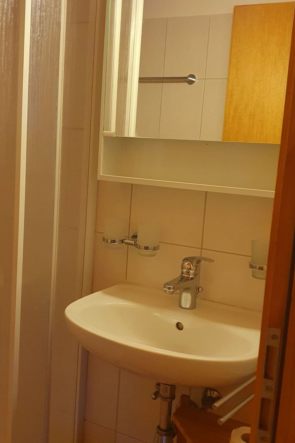 Une salle de bain avec un lavabo blanc, un miroir et un meuble en bois.
