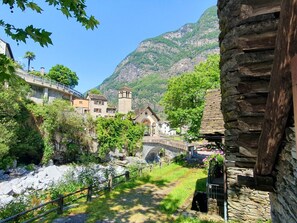 Un puente de piedra sobre un río, rodeado de abundante vegetación y edificios tradicionales.