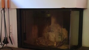 A fireplace with a glass front, a white mantel, and a tiled floor.