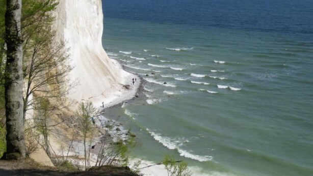Una scogliera a picco sul mare con una spiaggia sottostante.