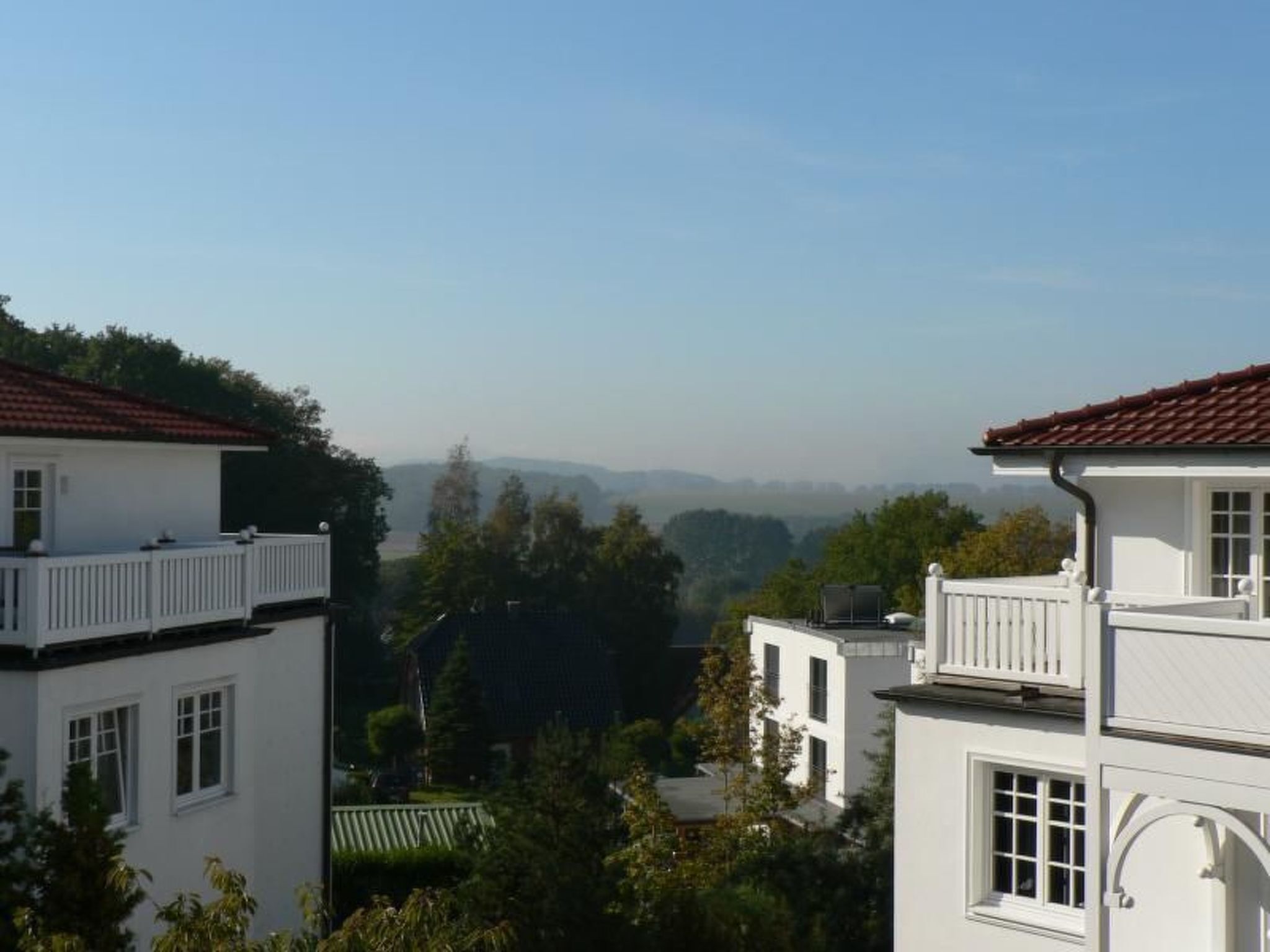 Un bâtiment blanc avec un toit recouvert de tuiles rouges, de nombreuses fenêtres et un balcon.