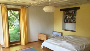 Une chambre à coucher avec un lit, une table de chevet, une bibliothèque et une fenêtre avec des rideaux.