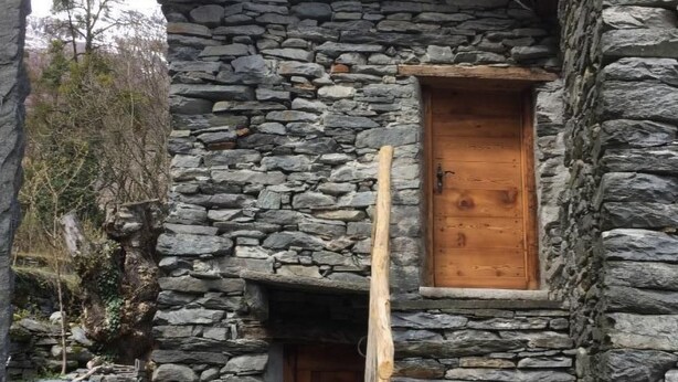 A stone building with a wooden door and a small window.