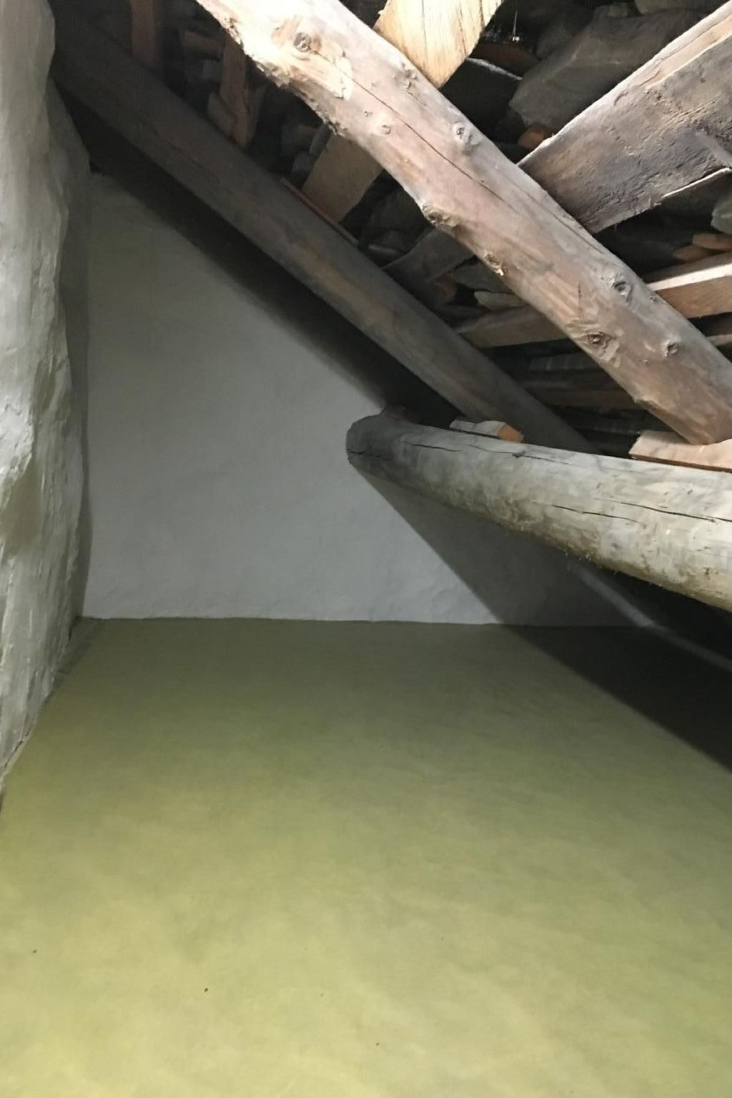 Une pièce avec un plafond en pente et des poutres en bois.