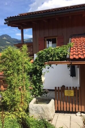 Ein traditionelles Chalet mit Holzfassade, einem Ziegeldach und einem kleinen Garten mit Steinfliesenbeet und Bambus.