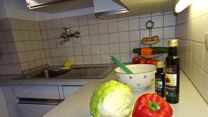 A kitchen with a sink, a bowl, vegetables, and bottles of oil on the counter. - Apartment Bärli by Interhome (Bad Bayersoien)