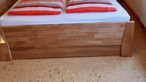 Un dormitorio con una cama de madera, almohadas a rayas, dos mesitas de noche y una decoración de pared con estrellas y texto.