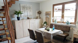 A dining area with a table, chairs, a staircase, and a window with a view.