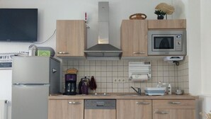 A modern kitchen with wooden cabinets, a built-in microwave, a coffee maker, and a dishwasher.