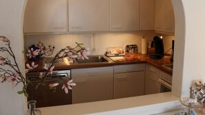 A kitchen with white cabinets, a toaster, a coffee maker, and a vase with flowers. - Residenza al Mulin by Interhome (Ascona)