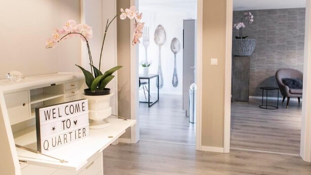 Een modern interieur met een welkomstbord, een potorkidee en een minimalistische eethoek met een stenen accentmuur.