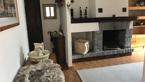 A cozy living room with a fireplace, a rug, a fur throw, and a bowl with a cat figurine.