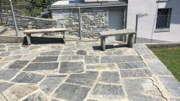 A stone patio with two benches and a stone wall.