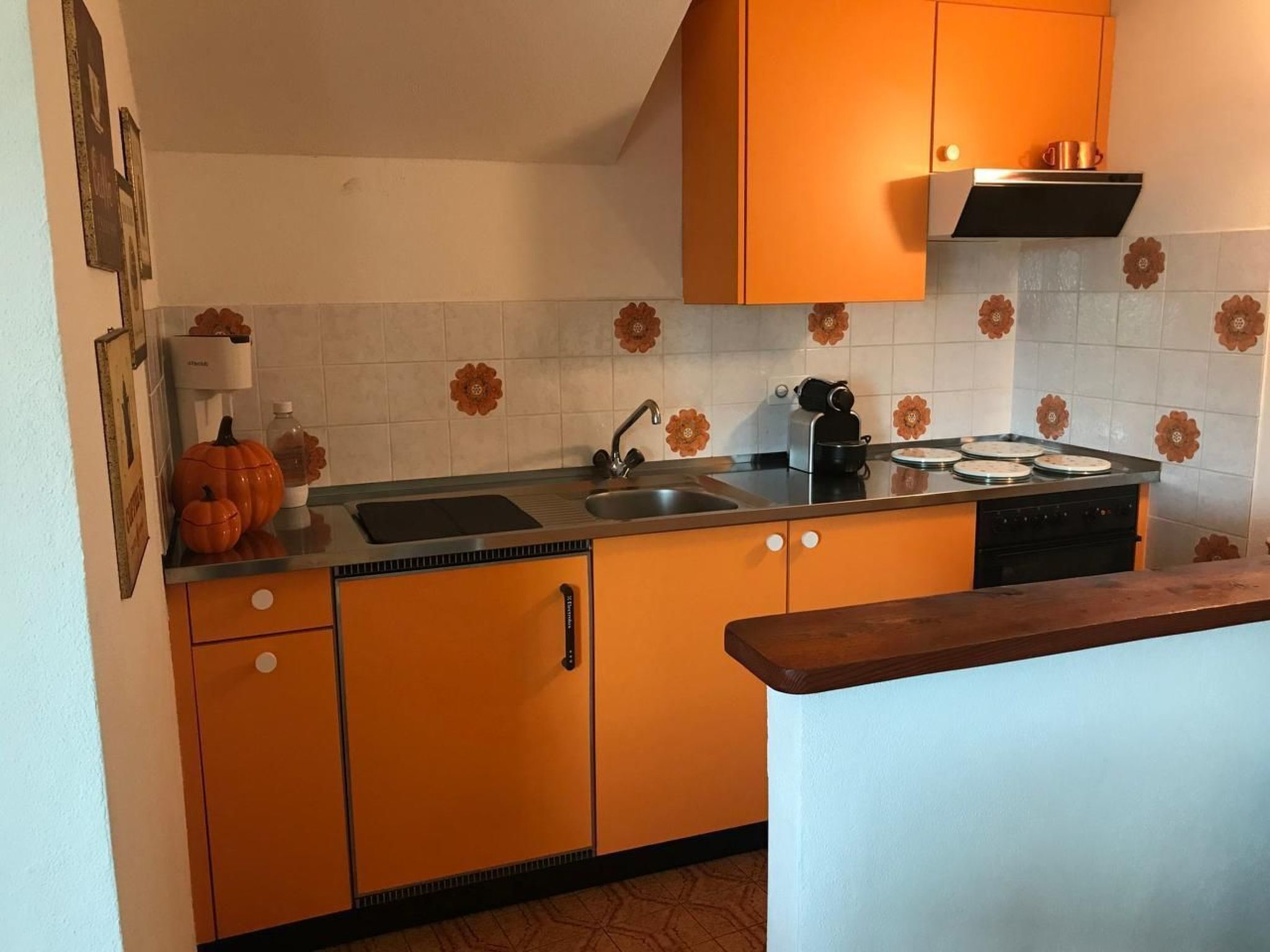 Una cucina con mobili arancioni, un lavello, un fornello e un piano di lavoro.