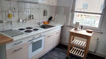 Een koelkast, een oven, kookgerei, borden en bestek