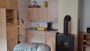 Une cuisine compacte avec des meubles en bois, un évier, une cuisinière et un petit coin repas comprenant une table et des chaises.