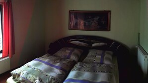 Une chambre avec un plafond en bois, un lit avec une literie à motifs, un tableau encadré au mur et un radiateur.