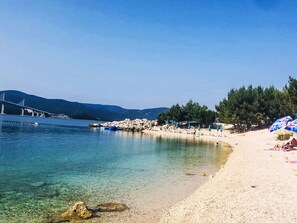 A beach with clear water, a rocky shoreline, and a bridge in the background. - Angenehme Wohnung in Komarna mit privatem Parkplatz by Interhome (Klek)