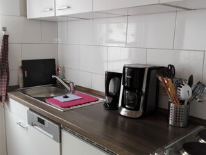 A modern kitchen with a stainless steel sink, a coffee maker, and a utensil holder. - Apartment Schenk by Interhome (Elbingerode)