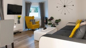 En moderne stue med sofa, gul lænestol og sofabord.